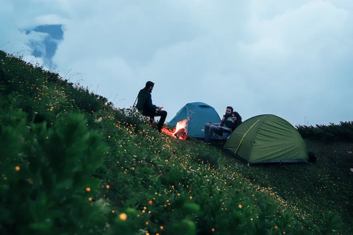 People Sitting Around a Campfire and Next to Their Tents